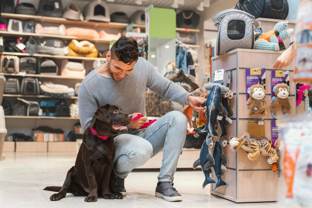 Cliente eligiendo juguetes y accesorios para su perro en una tienda de mascotas.